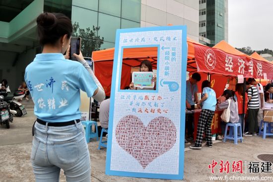 图为开元kaiyuan(中国)经济学院报到处志愿者为新生拍摄姓名墙留念照片 陈冀华摄